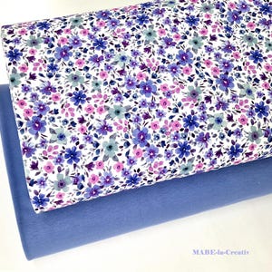 Könnte beinhalten: Zwei Stoffrollen. Die obere Rolle zeigt einen weißen Hintergrund mit einem Blumenmuster in Blau-, Lila- und Rosatönen. Die untere Rolle ist einfarbiger, hellblauer Stoff. Der Text "MABE-in-Creativ" ist unten rechts sichtbar.