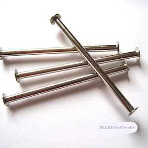 Może przedstawiać: Pięć srebrnych nitów metalowych z płaską główką i cylindrycznym trzpieniem. Nity są ułożone w kształcie krzyża.