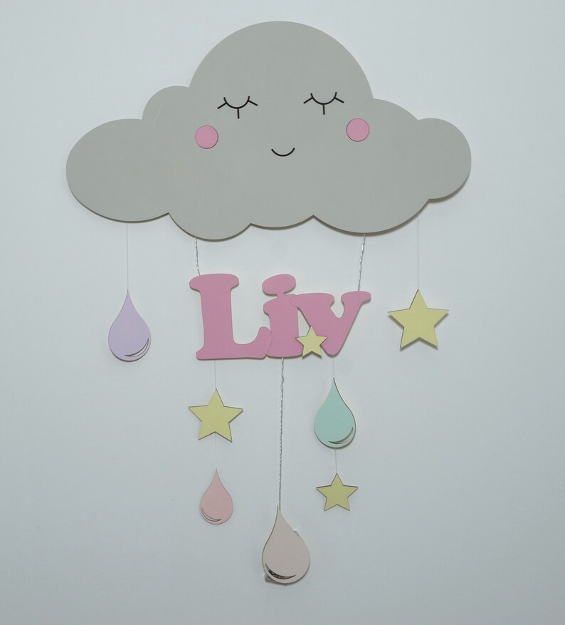 May include: A gray wooden cloud with a smiling face and pink cheeks hangs from the ceiling with pink, purple, and green raindrops and yellow stars. The name "Liv" is spelled out in pink letters below the cloud.