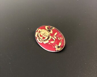 Dark red enameled brooch with gold color and black flowers design