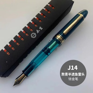May include: A turquoise fountain pen with a gold trim and a gold nib. The pen is in a black box with a red and white pattern. The box has the text "Sailor" on it. The pen is labeled "J14 教青半透明墨头 钛金笔".
