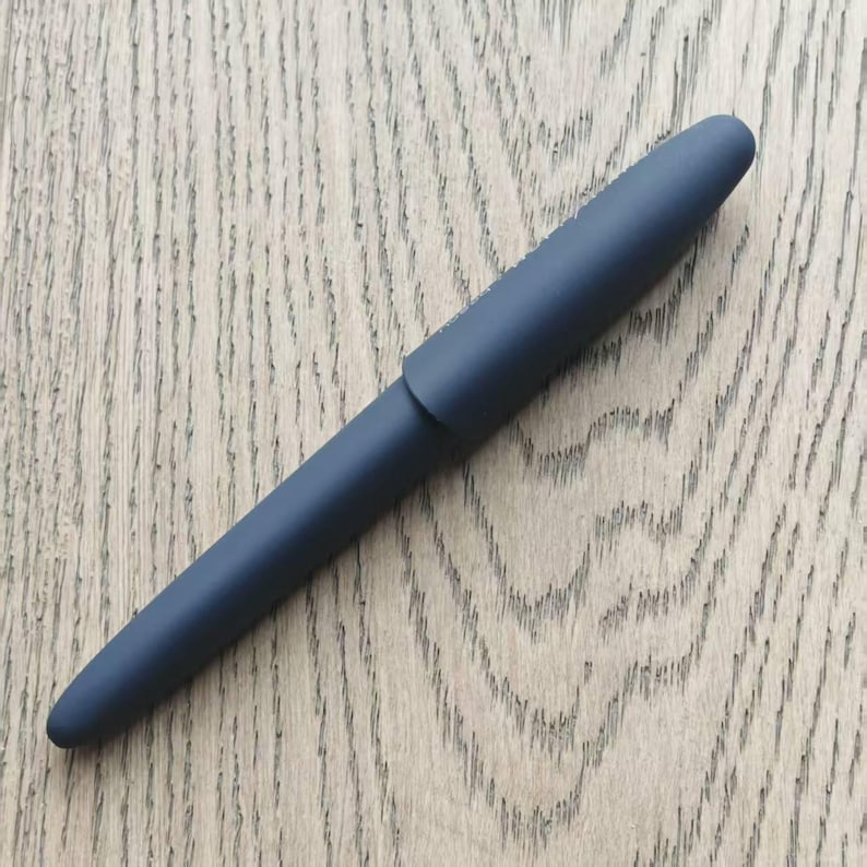 May include: A dark blue pen with a rounded cap and a smooth, matte finish.