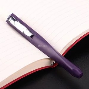 May include: A purple fountain pen with a silver trim and the words "St Penpps" printed on the side.