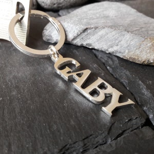 Könnte beinhalten: Silberner Schlüsselanhänger mit dem gravierten Namen "GABY".