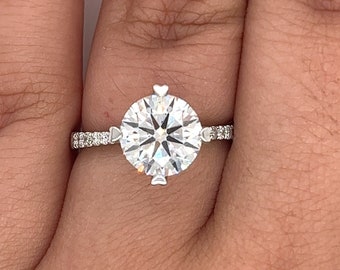 May include: A silver engagement ring with a large round diamond center stone and a pave diamond band.
