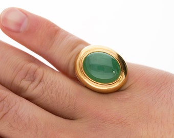 May include: A gold ring with a large oval green gemstone set in a double bezel.