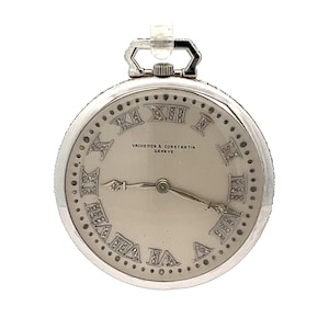 May include: A silver pocket watch with a white face and Roman numeral hour markers set with diamonds. The watch has a Vacheron Constantin Geneve inscription.