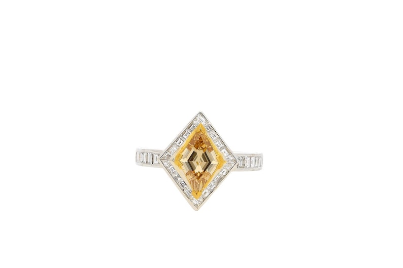 May include: A diamond ring featuring a yellow centre stone set in a diamond halo. The ring is crafted from white gold and has a square design.