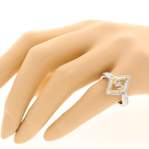 May include: A white gold ring featuring a square-shaped yellow diamond set within a halo of smaller diamonds.