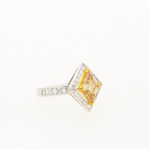 May include: A gold and silver ring featuring a large, square-shaped, yellow gemstone surrounded by smaller diamonds.