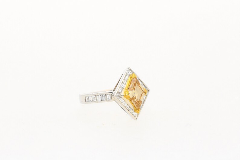 May include: A gold and silver ring featuring a large, square-shaped, yellow gemstone surrounded by smaller diamonds.