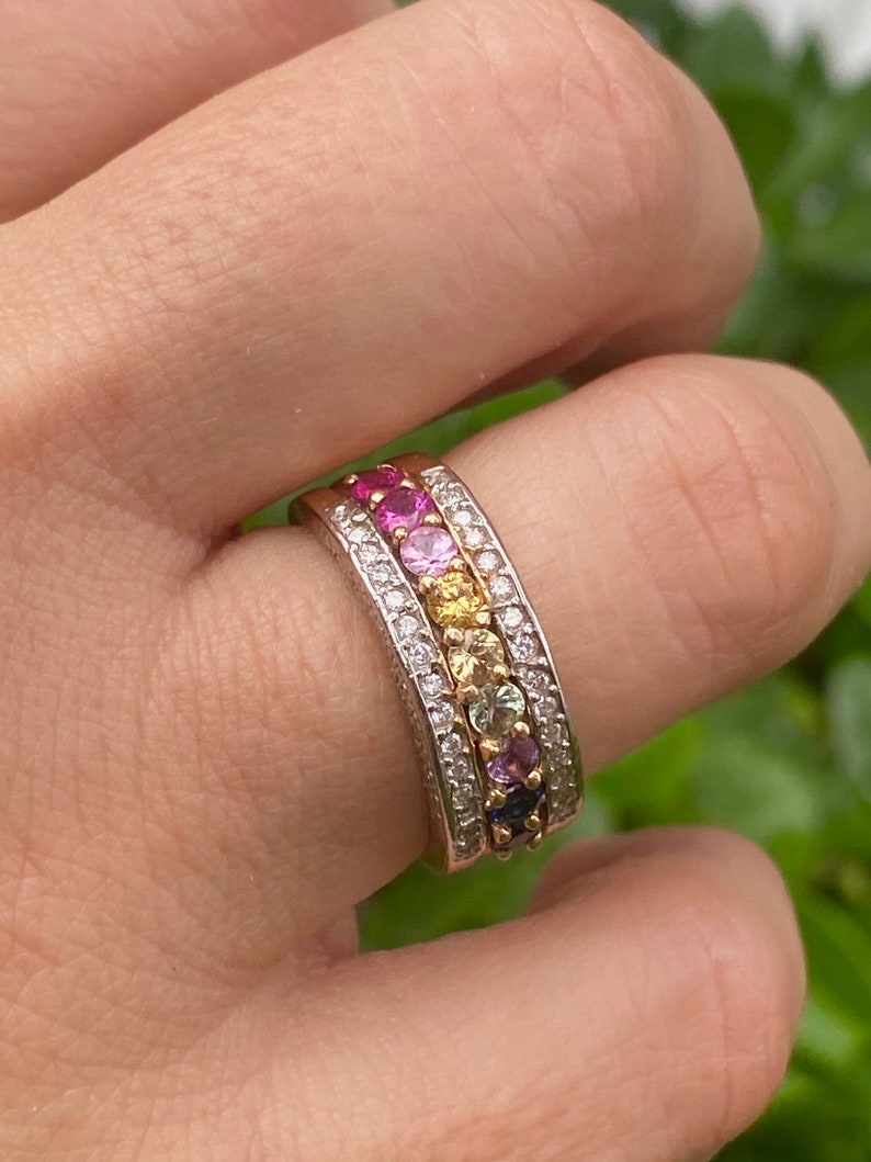 May include: A gold and silver ring with a rainbow of gemstones set in a band of diamonds.