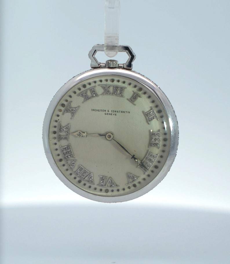 May include: A silver pocket watch with a white face and diamond Roman numeral hour markers. The watch face also has the text "VACHERON & CONSTANTIN GENEVE".