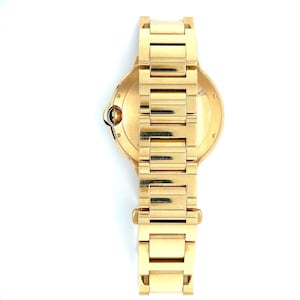 May include: A gold-tone wristwatch with a round face and a gold-tone metal strap.