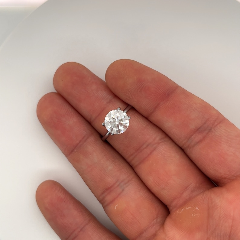 May include: A silver ring with a large, round, clear diamond.