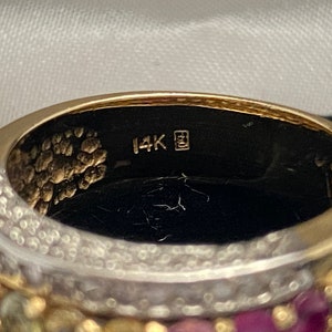May include: Close-up of the inside of a gold ring with a 14K stamp. The ring is decorated with small gemstones.
