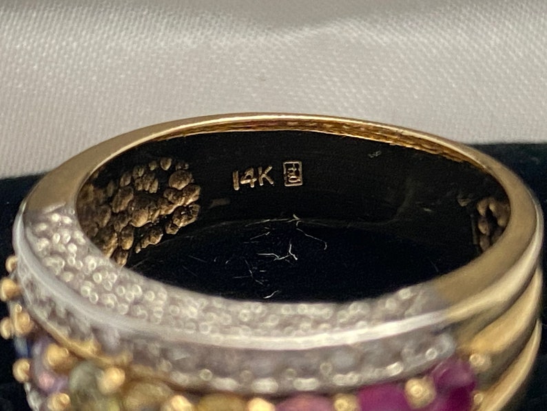 May include: Close-up of the inside of a gold ring with a 14K stamp. The ring is decorated with small gemstones.