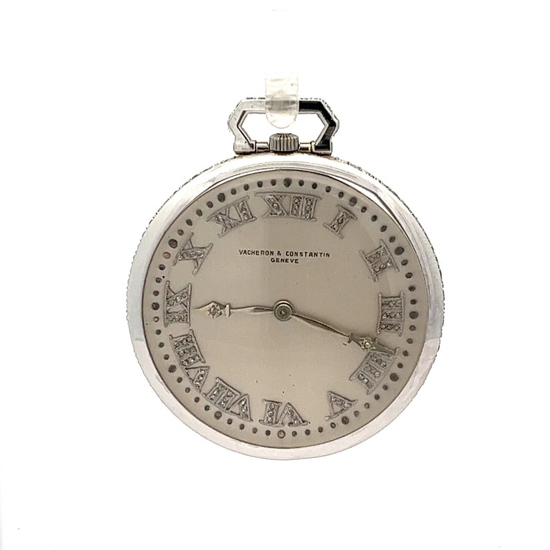 May include: A silver pocket watch with a white face and Roman numeral hour markers set with diamonds. The watch has a Vacheron Constantin Geneve inscription.
