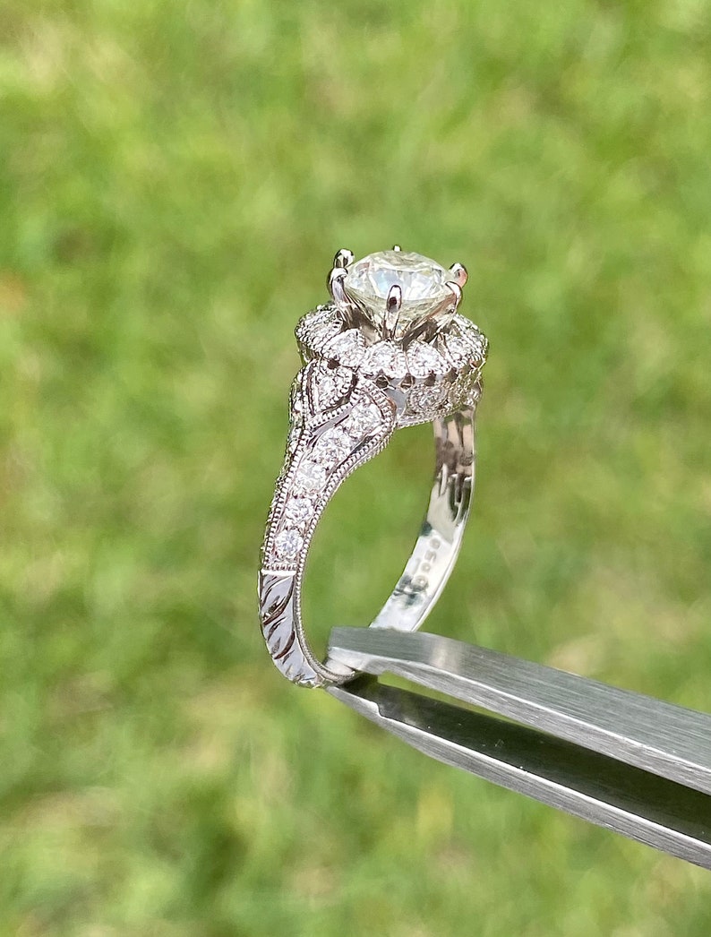 May include: A silver engagement ring with a large, round, clear diamond center stone. The ring has a delicate, intricate design with smaller diamonds set around the center stone and along the band.