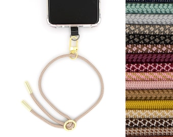 May include: A phone case with a gold clasp and a beige and brown patterned lanyard. The lanyard has a gold ring at the bottom. The image also shows a variety of different coloured lanyards.