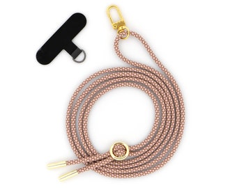 May include: A pink braided phone lanyard with a gold clasp and a gold ring. The lanyard is coiled and ready to be used.