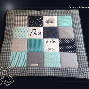Può includere: Una trapunta per neonati in patchwork verde, grigio e bianco con un'auto e il nome "Theo" ricamato. La trapunta ha anche la data "6. Juni 2016" ricamata.