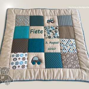 Op de afbeelding: Een blauwe en bruine patchwork babydeken met een tractor en auto applicatie. De deken is gepersonaliseerd met de naam "Fiete" en de datum "2. August 2018 2020".