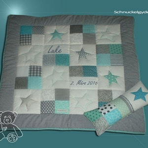 Könnte beinhalten: Eine weiße und graue Patchwork-Babydecke mit blauen Sternen und dem Namen "Luke" bestickt. Die Decke hat einen grauen und weißen karierten Rand. Ein passendes Kissen mit einem blauen Stern ist im Lieferumfang enthalten.