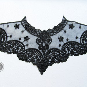 Könnte beinhalten: Schwarze Spitzenborte mit einem gewellten Rand und filigranen Blumendesigns. Die Spitze ist zart und durchscheinend und eignet sich perfekt, um jedem Projekt einen Hauch von Eleganz zu verleihen.