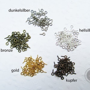 Könnte beinhalten: Sortiment kleiner Metallösen-Schraubenverschlüsse in verschiedenen Farben, darunter Bronze, Gold, Kupfer, Dunkel Silber und Hell Silber. Die Verschlüsse sind in fünf Stapeln auf einer weißen Oberfläche angeordnet.