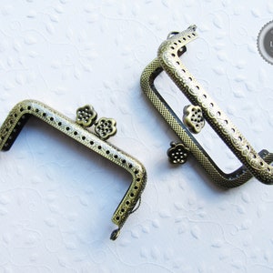 Könnte beinhalten: Zwei antike goldfarbene Metalltaschenrahmen mit verzierten Blumendesigns. Die Rahmen sind offen und bereit für ein DIY-Projekt.