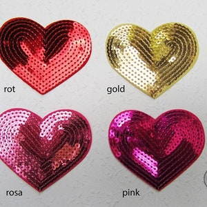Könnte beinhalten: Vier herzförmige Pailletten-Patches in den Farben Rot, Gold, Pink und Rosa. Die Patches haben einen Durchmesser von etwa 12,5 cm.