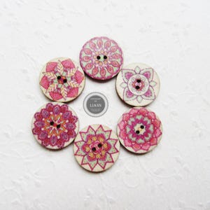 May include: A collection of six wooden buttons with floral mandala designs in shades of pink, red, and cream. Each button has two holes for sewing. The buttons are arranged in a circular pattern.