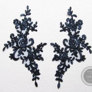 Könnte beinhalten: Zwei schwarze Spitzenapplikationen mit floralen Designs. Die Applikationen sind zart und filigran, mit einer Vielzahl von Blütenformen und -größen.