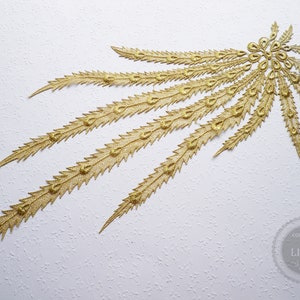 Könnte beinhalten: Goldfarbener Stoffbesatz mit einem Pfauenfeder-Design. Der Besatz ist aus Pailletten und Perlen gefertigt und hat eine glitzernde Oberfläche.