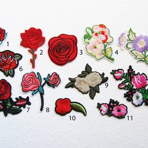Könnte beinhalten: Zwölf gestickte Bügelbilder mit verschiedenen Blumenmotiven, darunter Rosen, Lilien und andere Blumen. Die Patches sind von 1 bis 12 nummeriert.