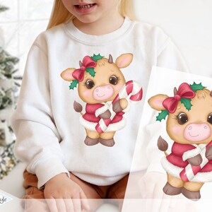 Könnte beinhalten: Eine niedliche Comic-Kuh, die ein rot-weißes Weihnachtsmannkostüm und eine rote Schleife mit grünem Stechpalmen trägt. Die Kuh hält einen Zuckerstock in ihrer rechten Huf.