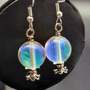 May include: A pair of iridescent blue and white glass bead earrings with silver hooks and decorative silver charms.