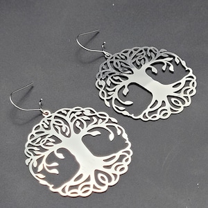 Peut inclure: Une paire de boucles d'oreilles en argent en forme d'arbre de vie. Les boucles d'oreilles sont en métal et ont un design délicat et complexe.