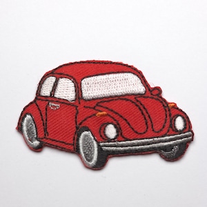 Könnte beinhalten: Gestickter Aufnäher mit einem roten Oldtimer mit weißen Fenstern und grauen Rädern. Der Aufnäher hat ein detailliertes Stichdesign, ideal zum Aufnähen auf Kleidung oder Accessoires. Das Auto hat Scheinwerfer und eine schwarze Stoßstange.
