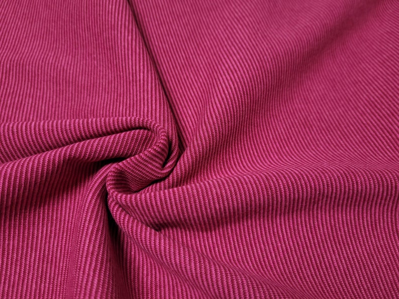 Peut inclure: Gros plan sur un tissu c&ocirc;tel&eacute; rose avec une texture subtile. Le tissu est pli&eacute; et drap&eacute;, mettant en valeur sa douceur et sa flexibilit&eacute;.