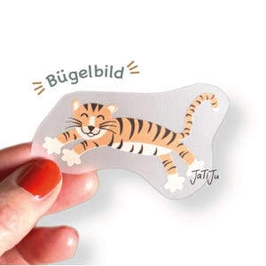 Könnte beinhalten: Ein transparentes Bügelbild mit einem Cartoon-Tiger in orangefarbenen und schwarzen Streifen, mit dem Text "Bügelbild" und der Signatur "JatiJu". Der Tiger wird in einer Laufpose mit einem lächelnden Gesicht dargestellt.