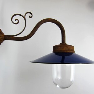May include: A vintage wall-mounted light fixture with a blue enamel shade and a rusty metal arm. The arm is decorated with a scroll design.