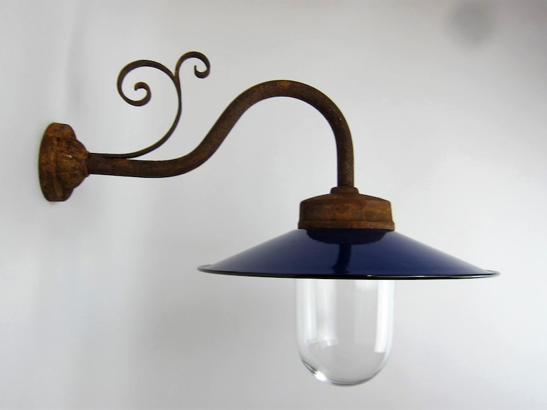 May include: A vintage wall-mounted light fixture with a blue enamel shade and a rusty metal arm. The arm is decorated with a scroll design.
