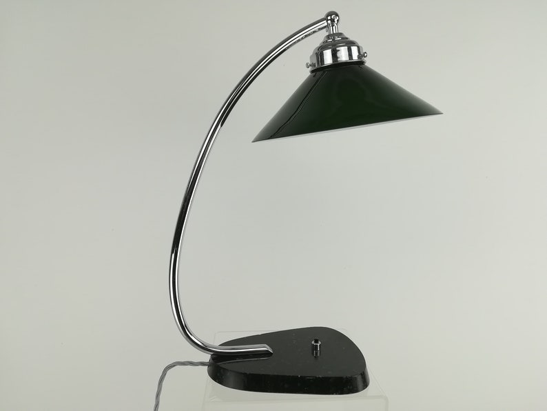 May include: A chrome desk lamp with a green shade. The lamp has a curved arm and a round base.