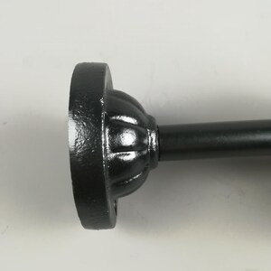 May include: Black metal curtain rod finial with a decorative fluted design.