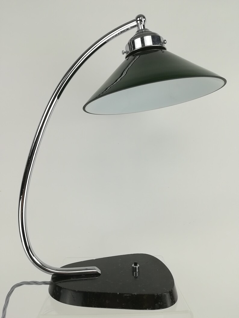 May include: A chrome desk lamp with a green glass shade and a black marble base.