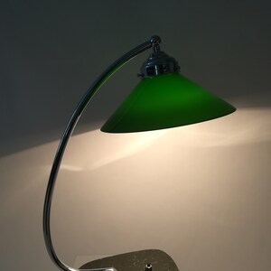 May include: A chrome desk lamp with a green glass shade and a dark green marble base.