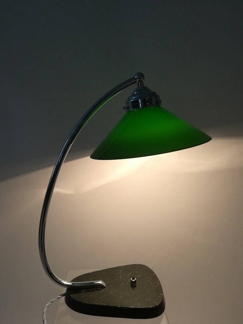 May include: A chrome desk lamp with a green glass shade and a dark green marble base.