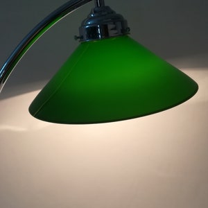 May include: A chrome desk lamp with a green glass shade. The lamp has a curved arm and a round base.